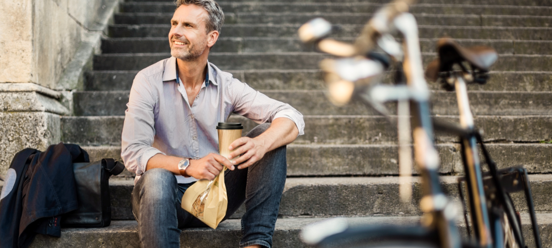 Homme sur un escalier avec un gobelet à café et un sachet à pain naturesse